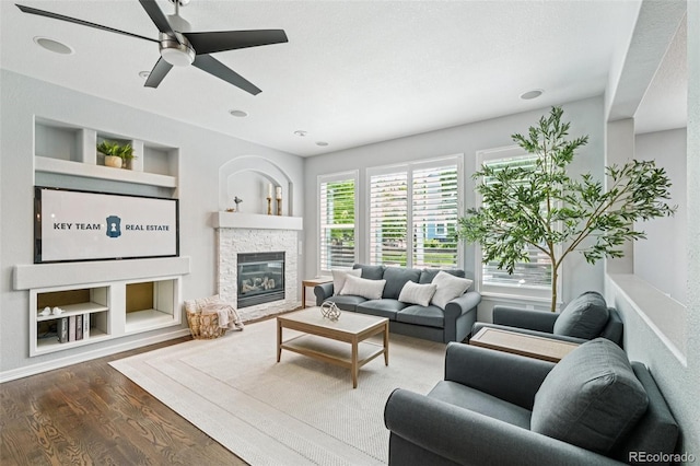 17020 E 107th Ave, Commerce City, CO 80022 - living area featuring wood finished floors, a ceiling fan, a stone fireplace, and built in features