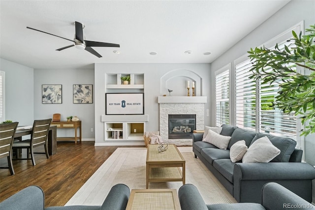 17020 E 107th Ave, Commerce City, CO 80022 - living room with wood finished floors, built in shelves, ceiling fan, and a stone fireplace