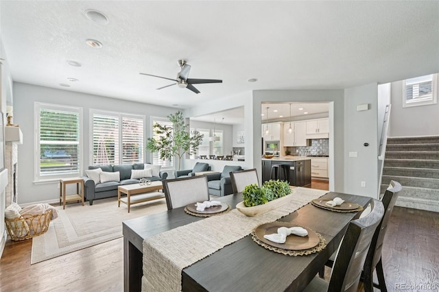 17020 E 107th Ave, Commerce City, CO 80022 - dining space featuring stairs, a ceiling fan, wood finished floors, and plenty of natural light