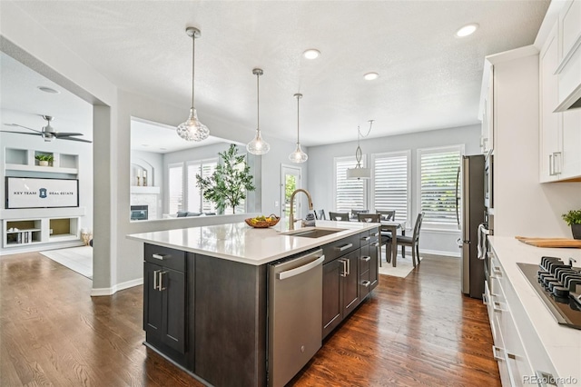 17020 E 107th Ave, Commerce City, CO 80022 - kitchen featuring appliances with stainless steel finishes, white cabinets, light countertops, a kitchen island with sink, and dark wood finished floors