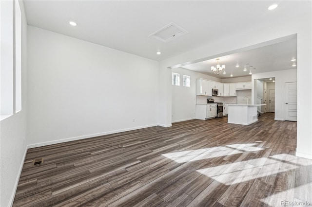 3295 N Coolidge Way, Aurora, CO 80019 - unfurnished living room featuring dark wood-style floors, baseboards, a chandelier, a sink, and recessed lighting