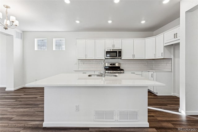 3295 N Coolidge Way, Aurora, CO 80019 - kitchen with stainless steel appliances, a sink, backsplash, dark wood-style floors, and white cabinetry