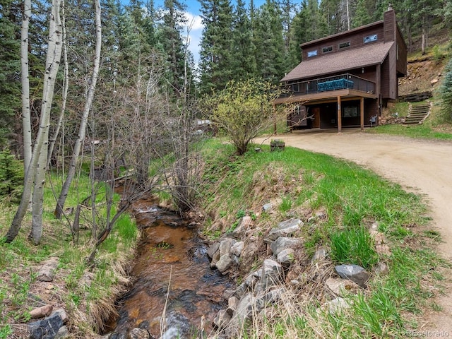 28272 Shadow Mountain Dr, Conifer, CO 80433 - view of front facade with driveway, a wooden deck, a chimney, stairway, and a shingled roof