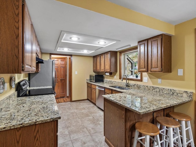 28272 Shadow Mountain Dr, Conifer, CO 80433 - kitchen with appliances with stainless steel finishes, a sink, a peninsula, a kitchen bar, and light stone countertops