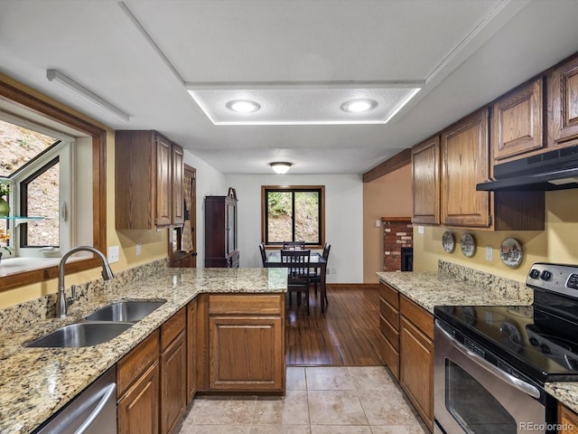 28272 Shadow Mountain Dr, Conifer, CO 80433 - kitchen with stainless steel appliances, under cabinet range hood, a sink, a peninsula, and light stone countertops