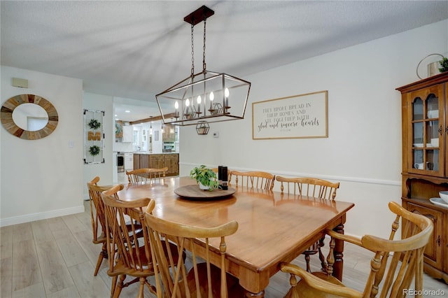 8043 S Zephyr St, Littleton, CO 80128 - dining room with light wood-type flooring, baseboards, and a chandelier