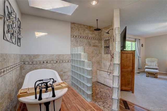 8043 S Zephyr St, Littleton, CO 80128 - bathroom with tile walls, a walk in shower, a freestanding tub, a skylight, and wainscoting