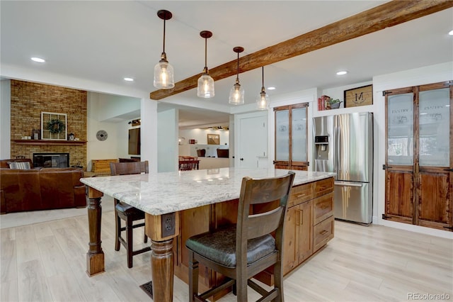 8043 S Zephyr St, Littleton, CO 80128 - kitchen featuring stainless steel refrigerator with ice dispenser, beam ceiling, light wood-style floors, light stone countertops, and a breakfast bar