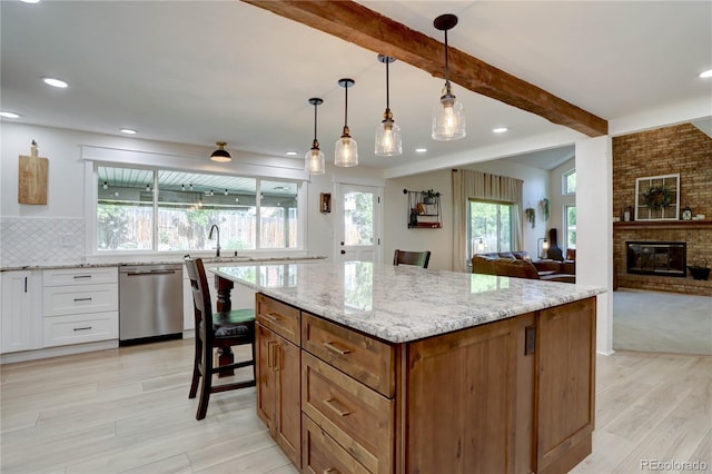 8043 S Zephyr St, Littleton, CO 80128 - kitchen with stainless steel dishwasher, beam ceiling, light wood finished floors, light stone counters, and white cabinetry