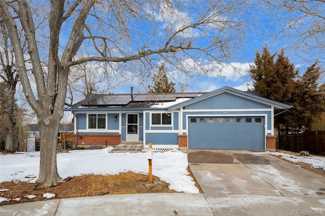 ranch-style house featuring a garage, brick siding, driveway, and solar panels