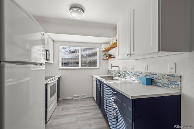 kitchen with white appliances, a sink, visible vents, white cabinetry, and light countertops