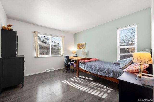 bedroom featuring baseboards, multiple windows, visible vents, and wood finished floors