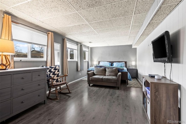 bedroom with dark wood-style flooring, multiple windows, and a drop ceiling