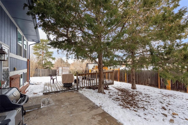 yard covered in snow featuring a fenced backyard, a patio, and a wooden deck