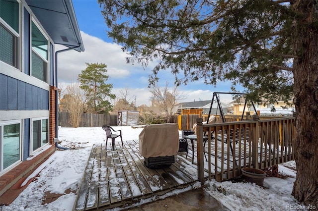 snow covered deck featuring a fenced backyard and grilling area