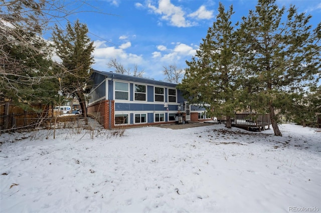 snow covered property featuring brick siding