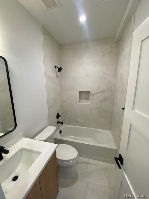 full bathroom featuring toilet, vanity, and tiled shower / bath