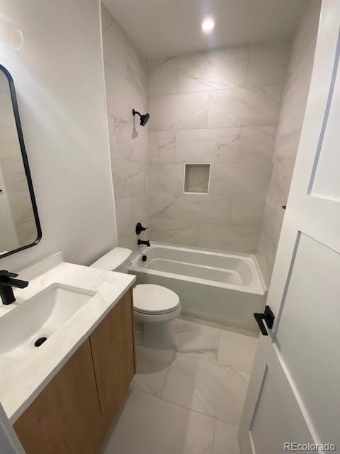 full bathroom with vanity, tiled shower / bath combo, and toilet