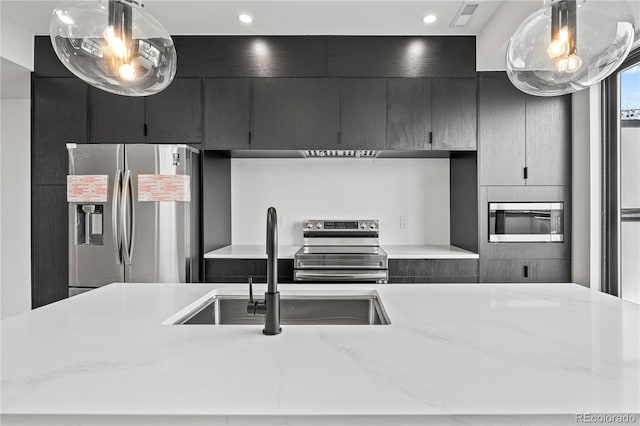 kitchen with dark cabinets, a sink, visible vents, appliances with stainless steel finishes, and pendant lighting