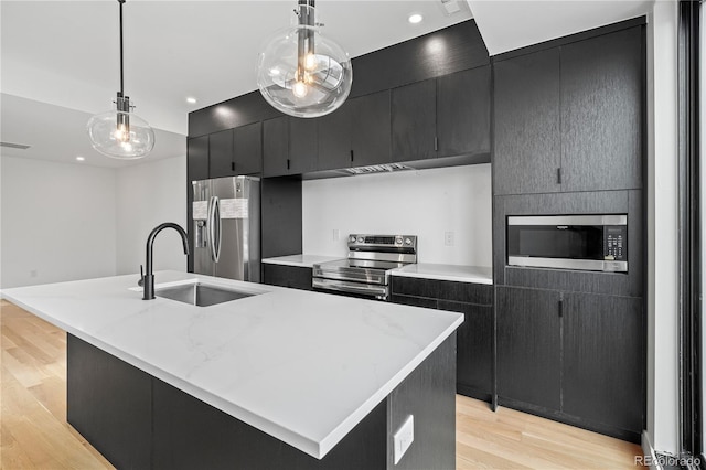 kitchen with stainless steel appliances, a sink, a kitchen island with sink, and decorative light fixtures