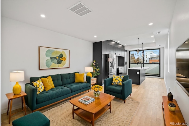 living area featuring baseboards, recessed lighting, visible vents, and light wood-style floors