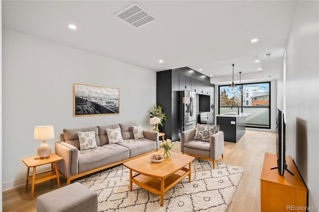 living room featuring recessed lighting, visible vents, and light wood-style flooring