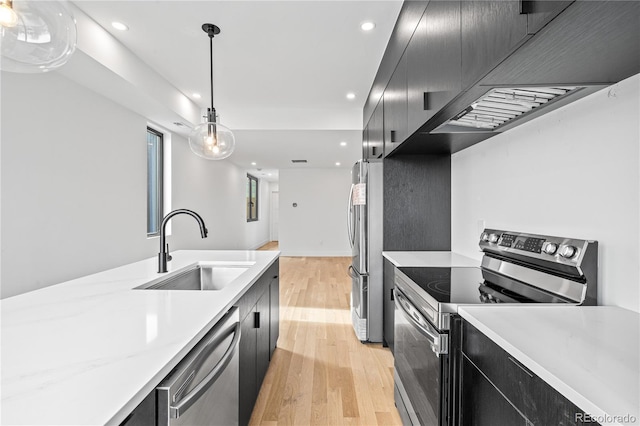 kitchen with appliances with stainless steel finishes, light countertops, dark cabinets, and decorative light fixtures