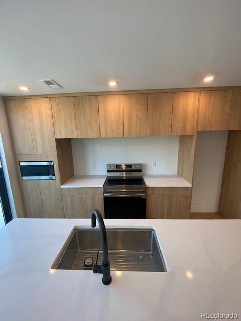 kitchen featuring electric range, visible vents, light countertops, and a sink