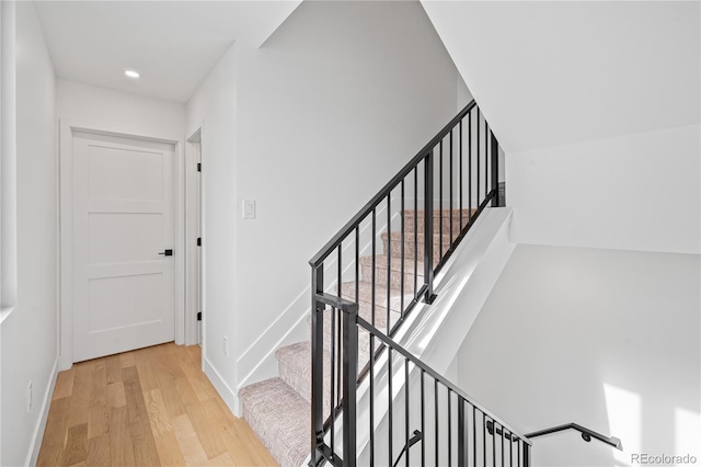 stairs featuring baseboards, wood finished floors, and recessed lighting