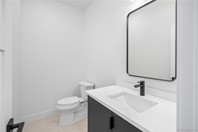 bathroom featuring toilet, baseboards, and vanity