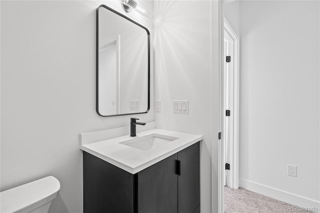 bathroom with baseboards, vanity, and toilet