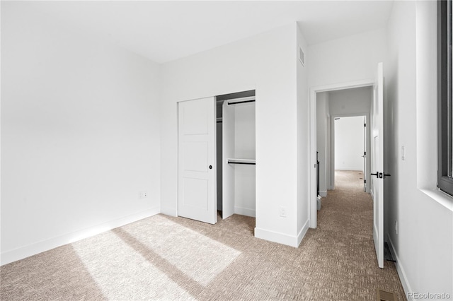 unfurnished bedroom featuring carpet floors, a closet, visible vents, and baseboards