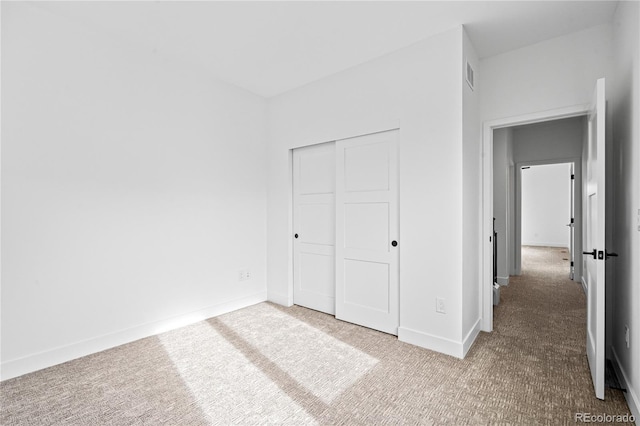 unfurnished bedroom featuring carpet floors, visible vents, baseboards, and a closet