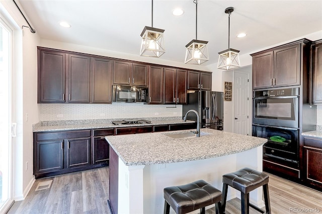 9835 Uravan St, Commerce City, CO 80022 - kitchen with black appliances, light wood-style flooring, backsplash, dark brown cabinetry, and recessed lighting