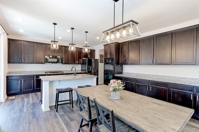 9835 Uravan St, Commerce City, CO 80022 - kitchen with black appliances, dark brown cabinetry, a sink, decorative backsplash, and light wood-style floors