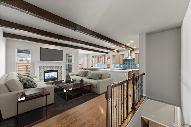 living room featuring a tiled fireplace and beamed ceiling