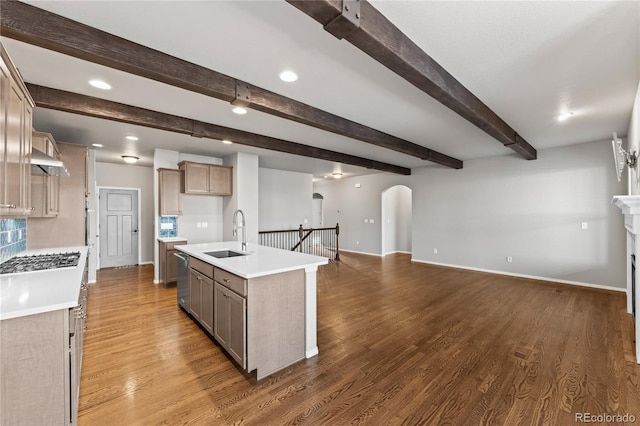 kitchen with beamed ceiling, an island with sink, sink, hardwood / wood-style flooring, and stainless steel appliances