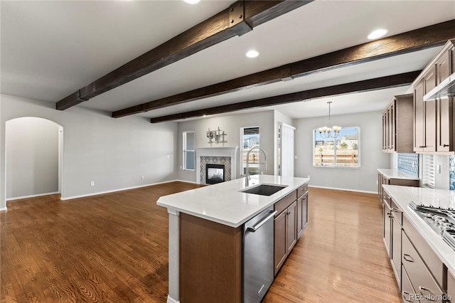 kitchen with appliances with stainless steel finishes, a fireplace, sink, a kitchen island with sink, and light hardwood / wood-style floors