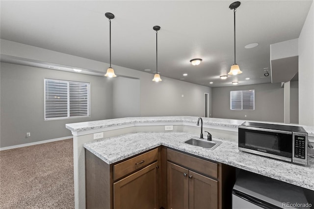 kitchen featuring stainless steel appliances, carpet flooring, sink, and hanging light fixtures