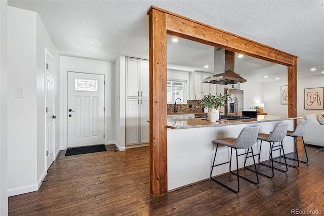 12345 W 32nd Ave, Wheat Ridge, CO 80033 - kitchen featuring light stone countertops, dark wood-type flooring, white cabinets, a breakfast bar, and island range hood