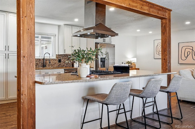 12345 W 32nd Ave, Wheat Ridge, CO 80033 - kitchen with stainless steel fridge with ice dispenser, a kitchen bar, dark wood finished floors, recessed lighting, and island range hood