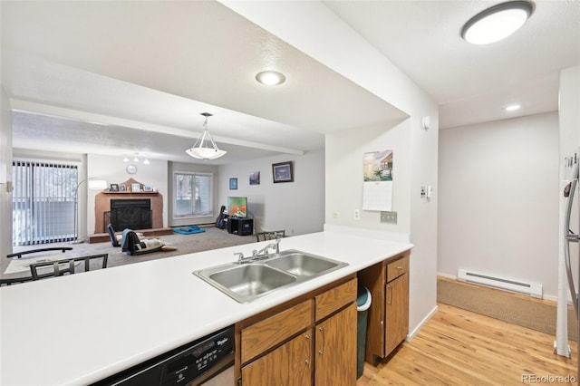 kitchen with light countertops, baseboard heating, light wood-style floors, brown cabinetry, and a sink