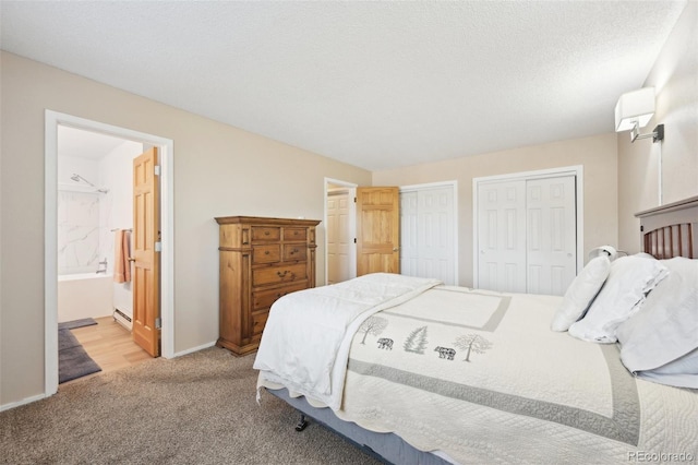 bedroom featuring two closets, baseboards, carpet floors, ensuite bathroom, and a textured ceiling