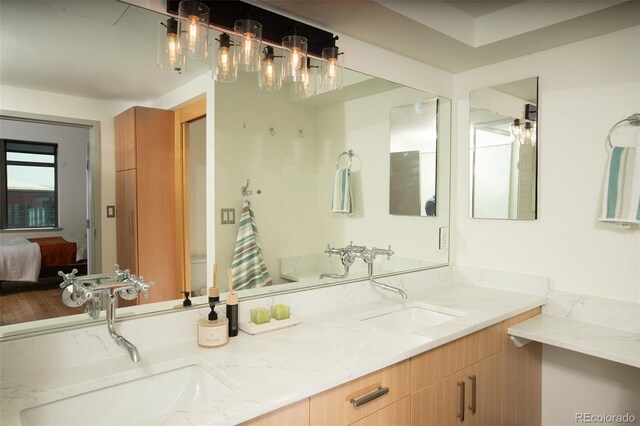 ensuite bathroom featuring double vanity, a sink, and connected bathroom