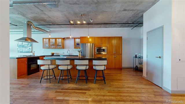 1401 Wewatta St Unit 808, Denver, CO 80202 - kitchen with stainless steel appliances, a breakfast bar, light wood finished floors, range hood, and a kitchen island
