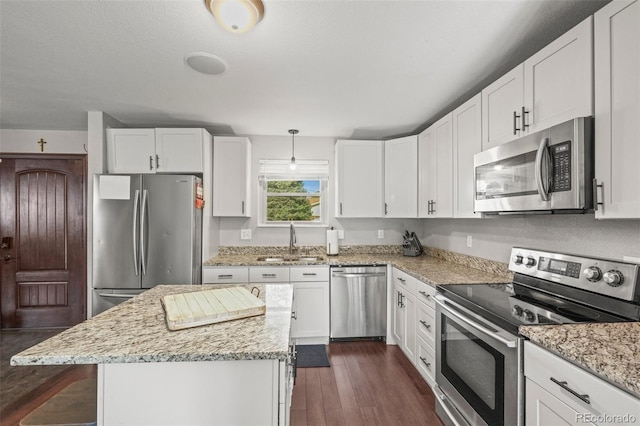 kitchen featuring dark wood-style flooring, light stone counters, a sink, white cabinetry, and appliances with stainless steel finishes