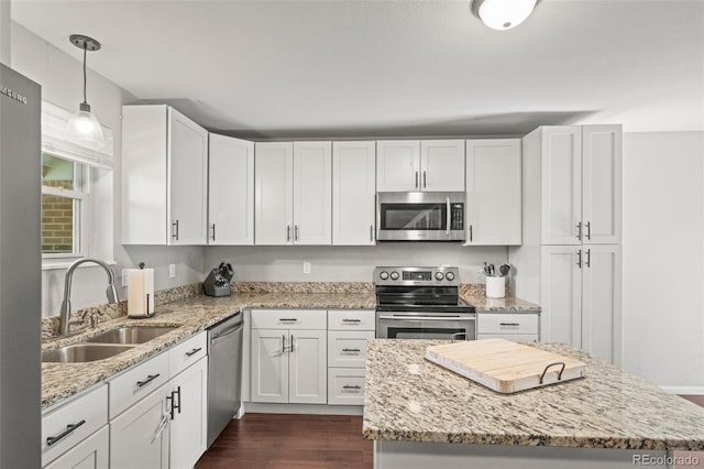 kitchen featuring a sink, stainless steel appliances, white cabinetry, dark wood finished floors, and a kitchen island