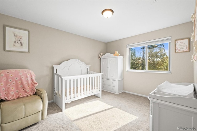 bedroom with light carpet, baseboards, and a nursery area