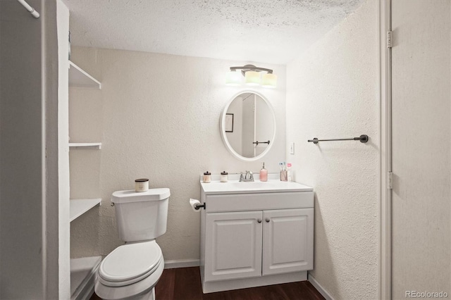 bathroom with toilet, wood finished floors, a textured ceiling, a textured wall, and vanity