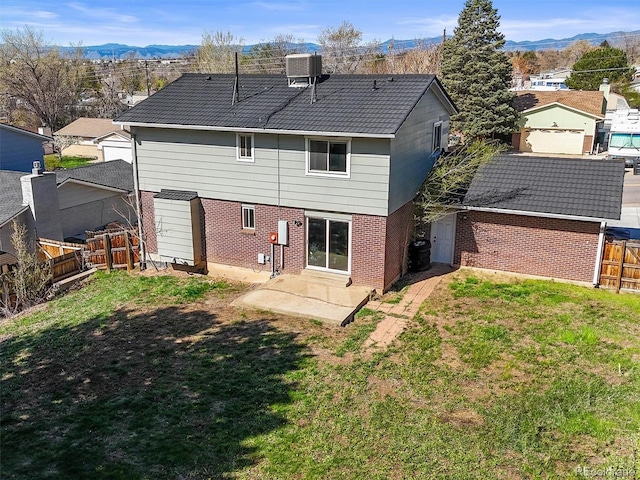 rear view of house with a yard, brick siding, a mountain view, and a fenced backyard